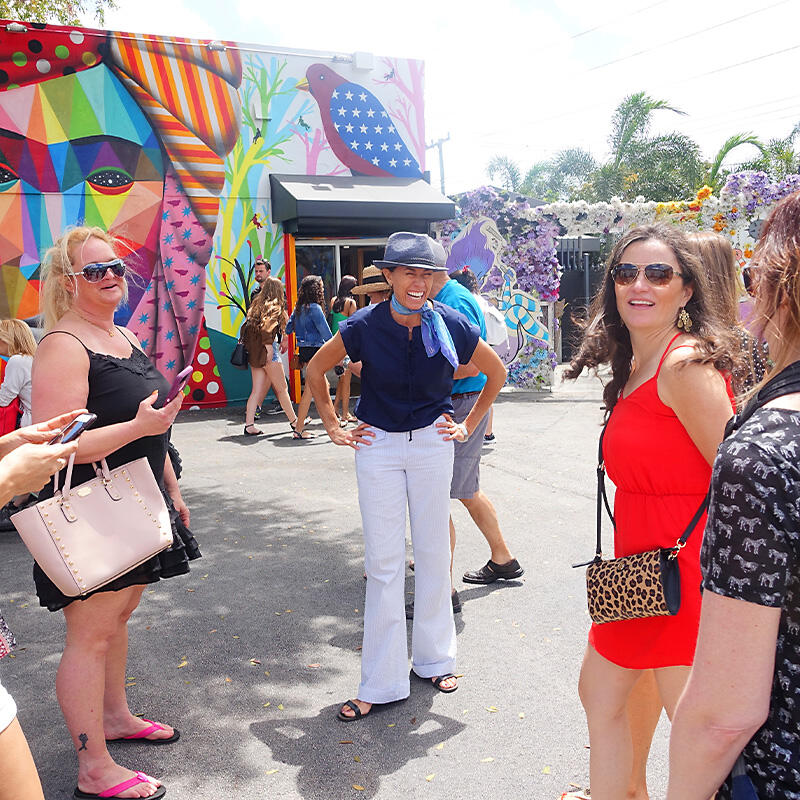 A group of people enjoying a culinary private experience in front of a colorful mural in Little Havana.