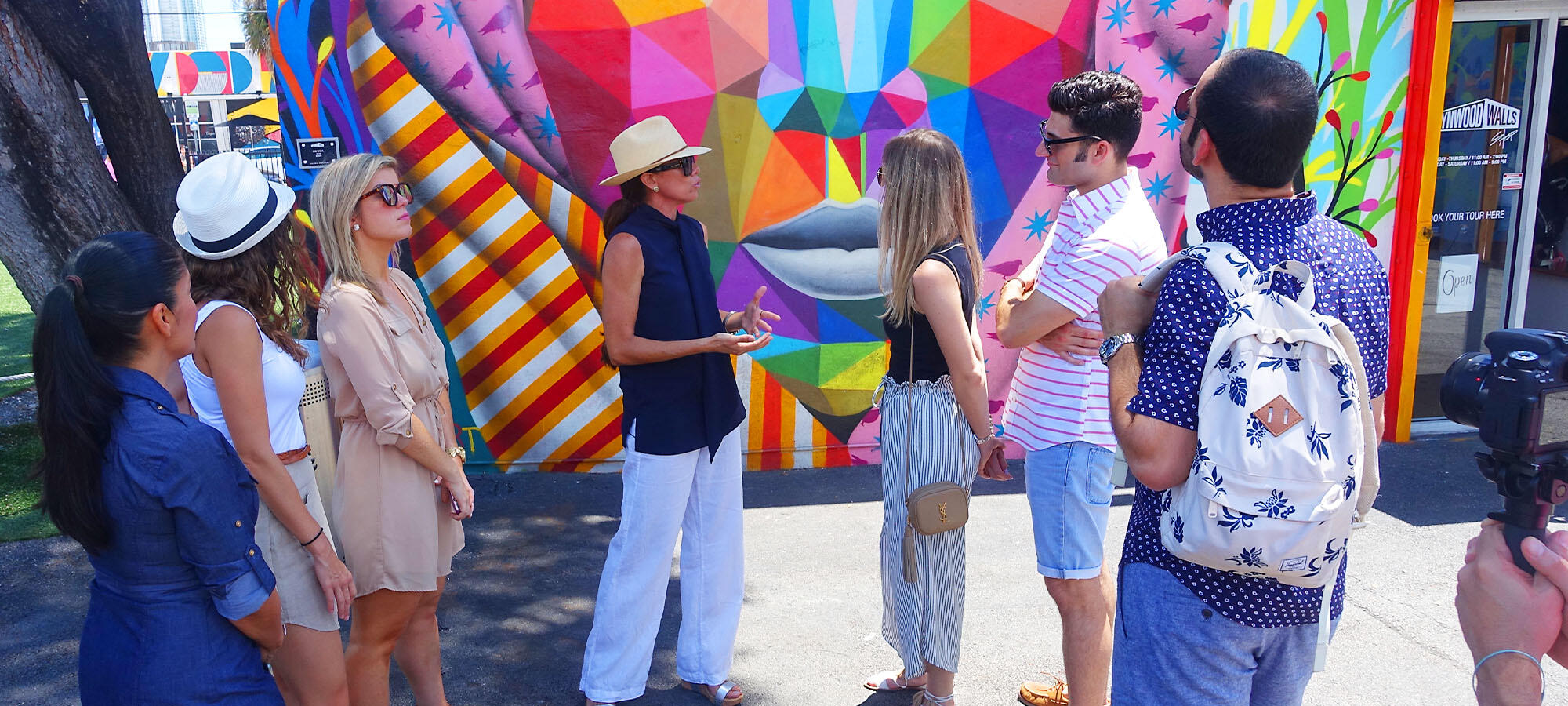 A group of people enjoying a private culinary experience in front of a colorful mural in Little Havana.
