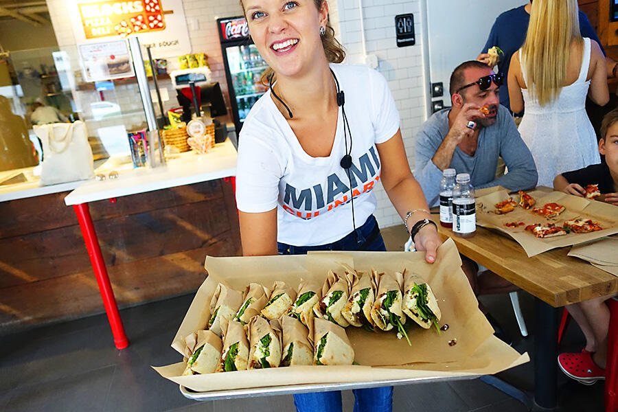 A culinary expert offering private experiences in Miami, showcasing a tray of delicious sandwiches at a local restaurant.