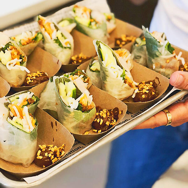 A culinary enthusiast is holding a tray of spring rolls during a private culinary experience.