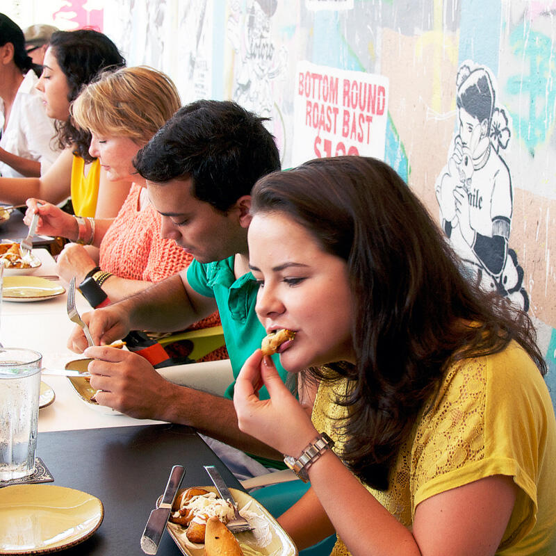 A group of people participating in a Miami Food Tour, sitting at a table and enjoying delicious food.