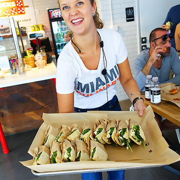 A woman showcasing a tray of wraps during a Miami Food Tour.