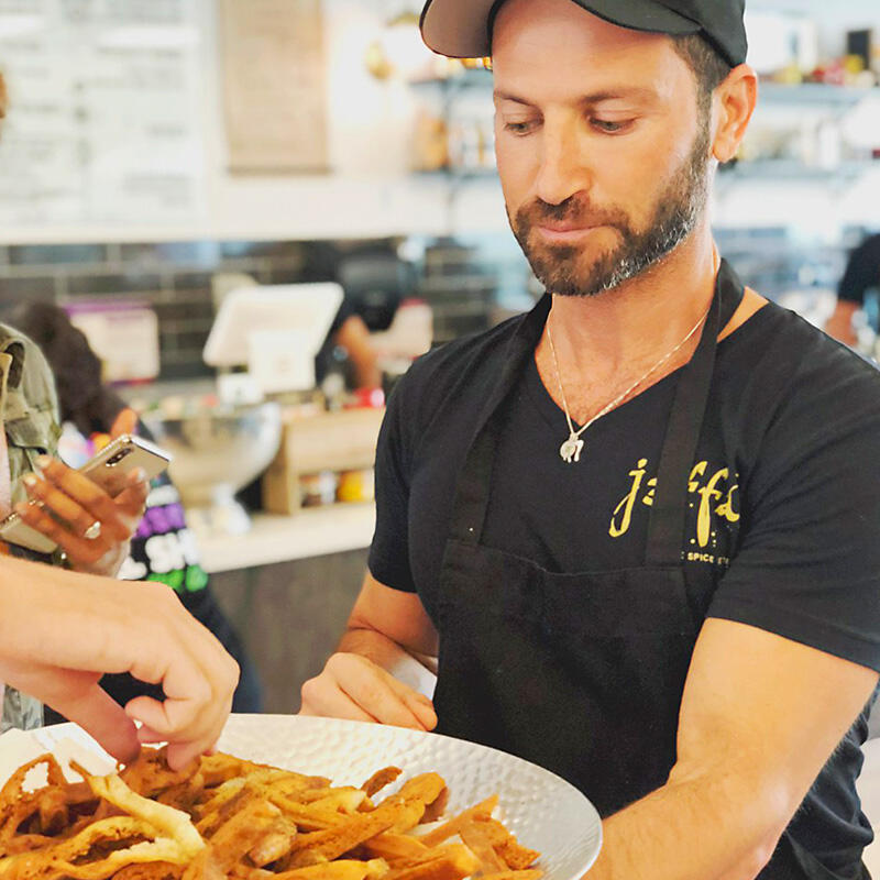 A man is handing a plate of french fries to a woman during a group tour.