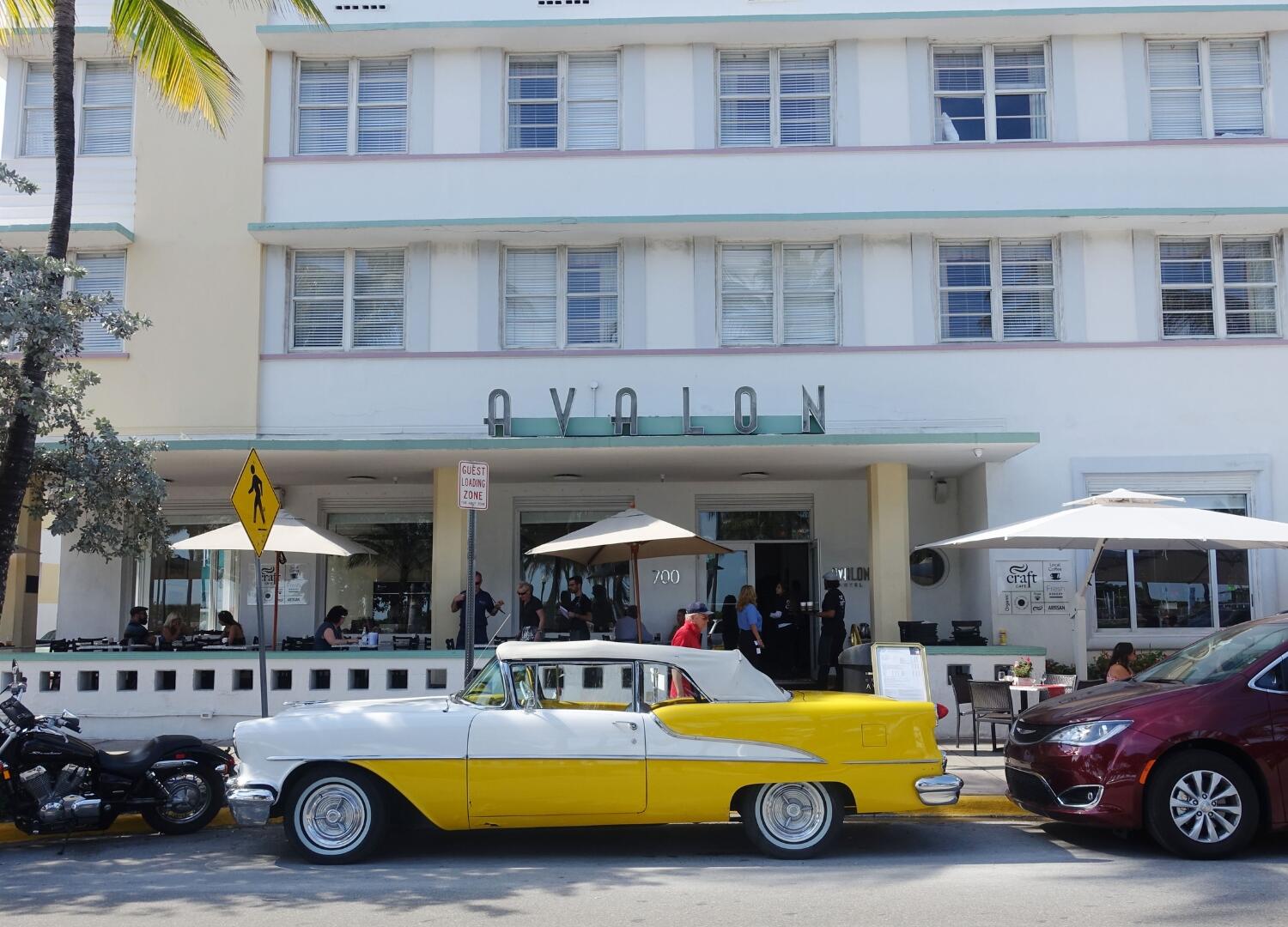 A classic car is parked in front of a hotel, offering a nostalgic touch to the Private Tours and Group Tours provided by the hotel.