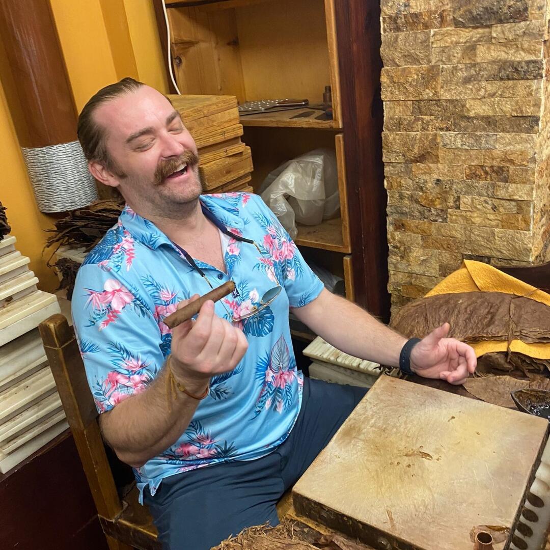 A man enjoying a private culinary tour in Miami, with cigars placed in front of him.