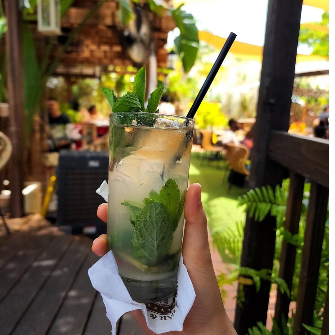 A person enjoying a glass of mojito on a wooden deck during private culinary tours in Miami.
