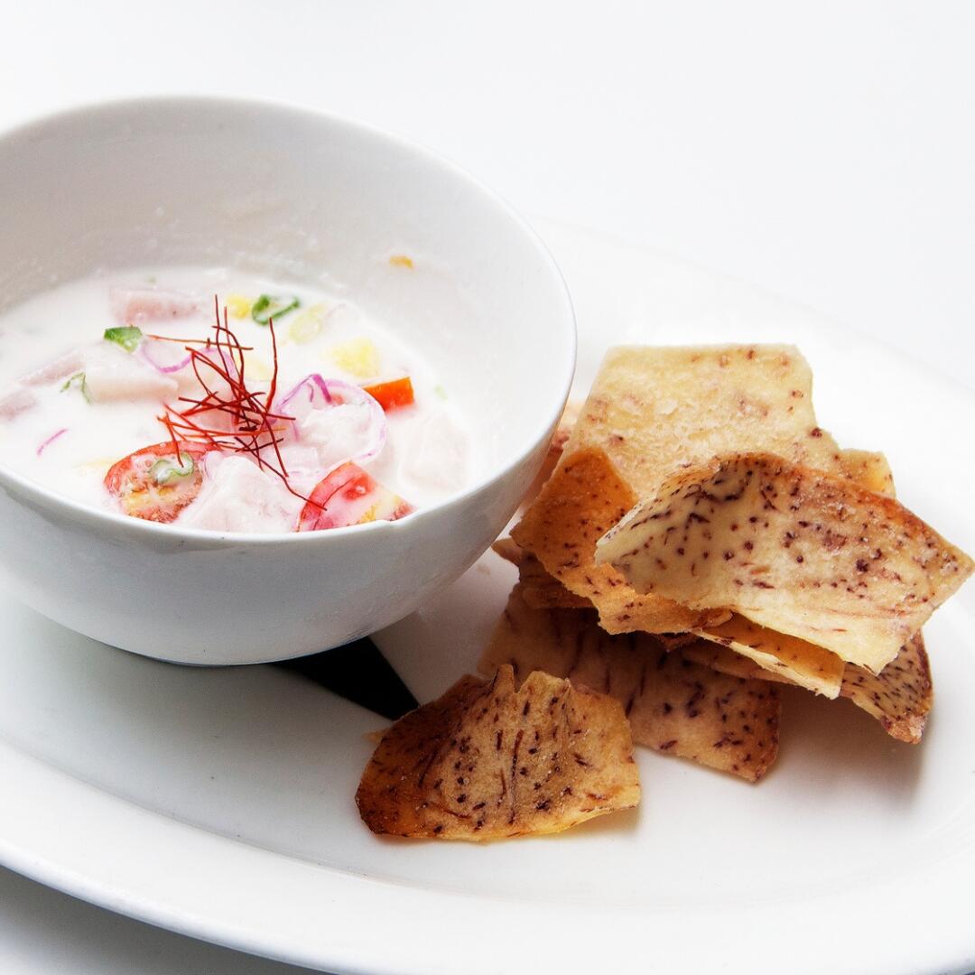 A bowl of dip and chips on a white plate during a culinary tour.