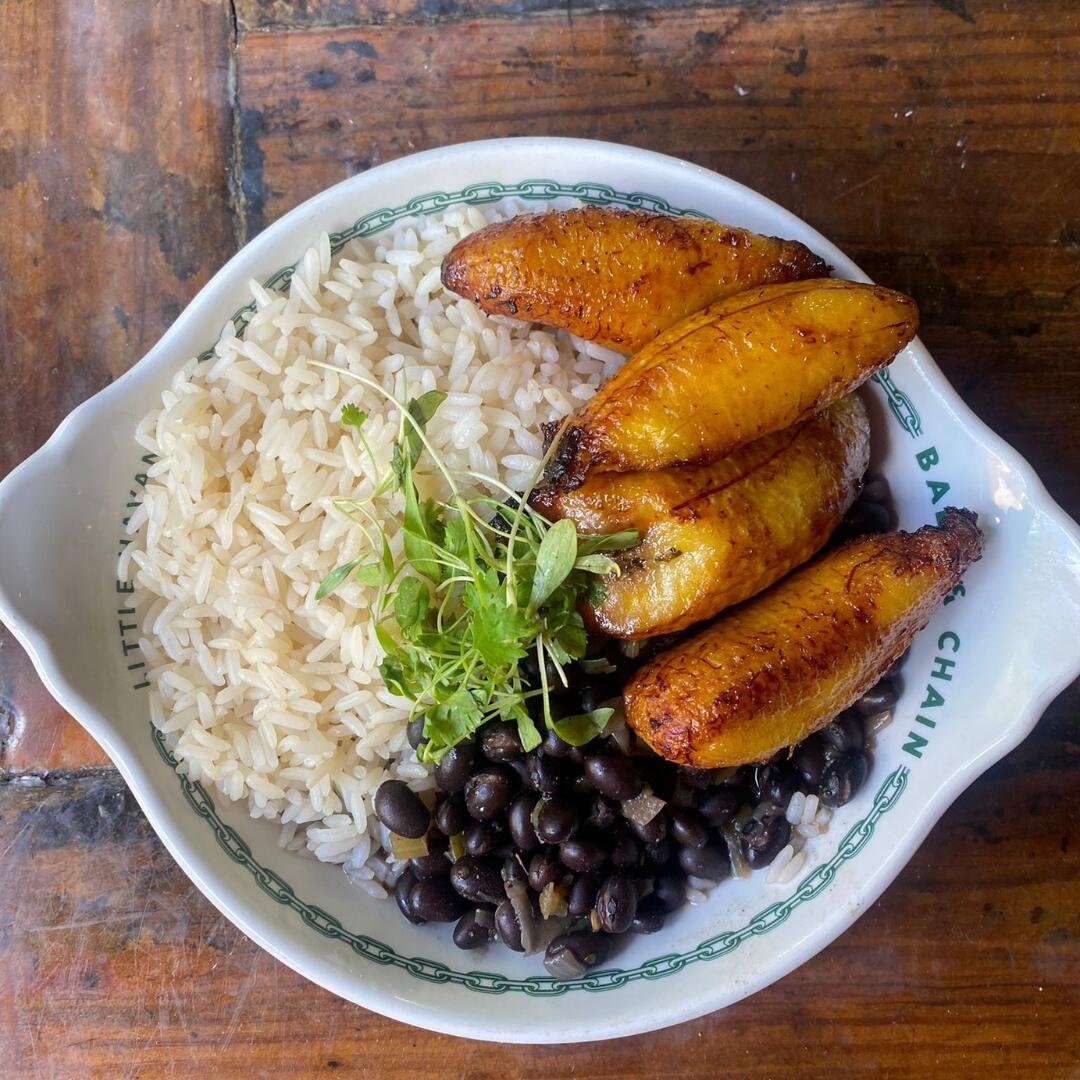 A plate of rice and black beans on a wooden table showcasing the culinary delights of Miami with Private Tours and Miami Food Tours.