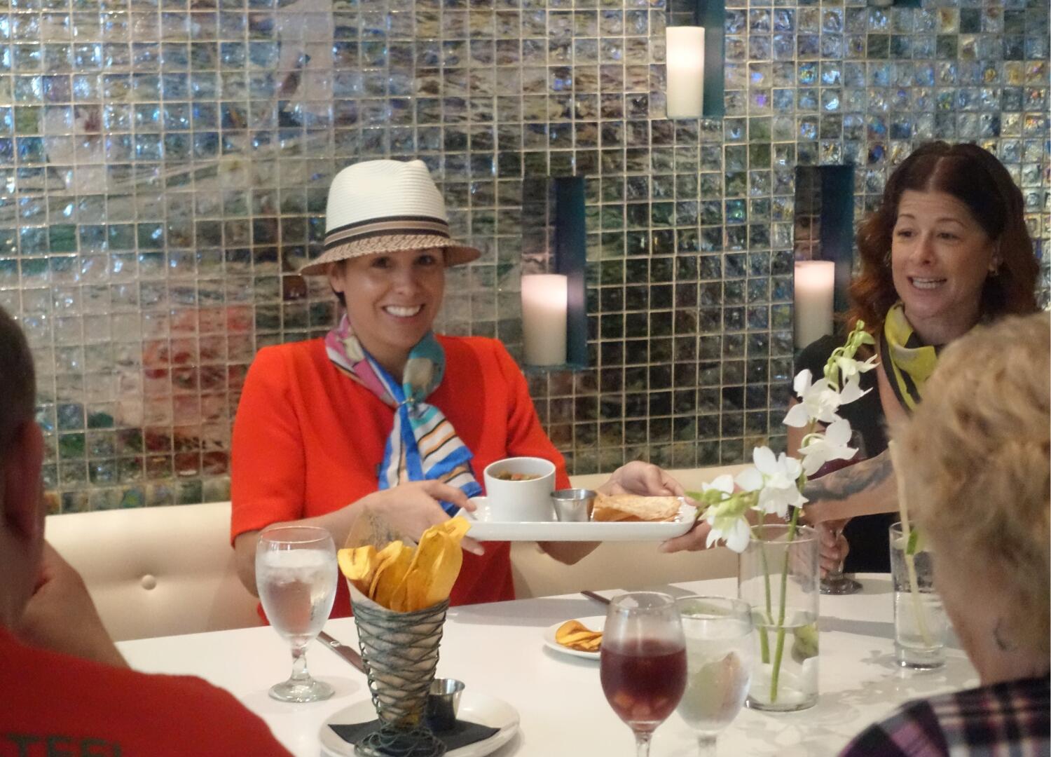 A group of people on a culinary tour sitting at a table with a tray of food.