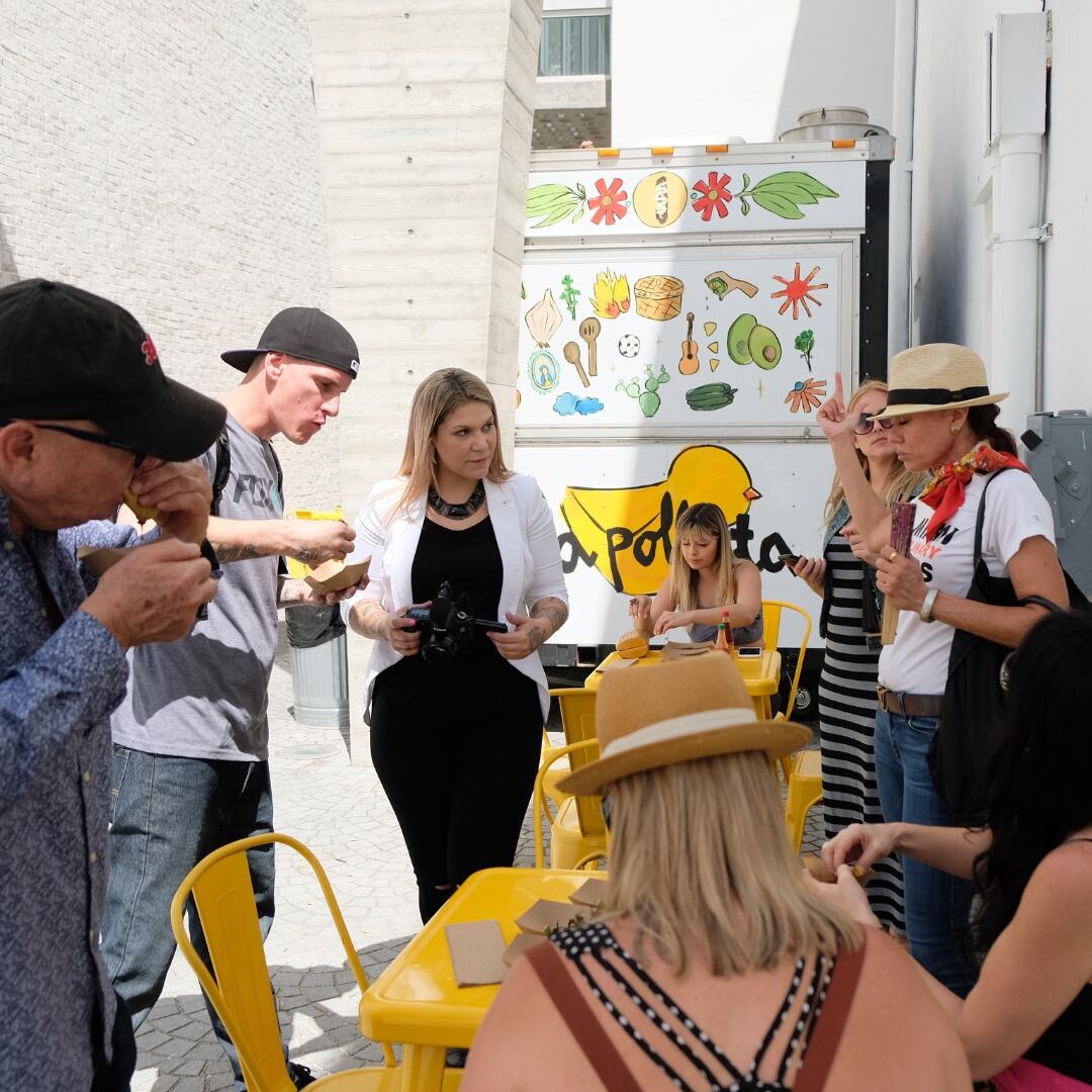 A group of people enjoying a Miami Food Tour around a food truck.