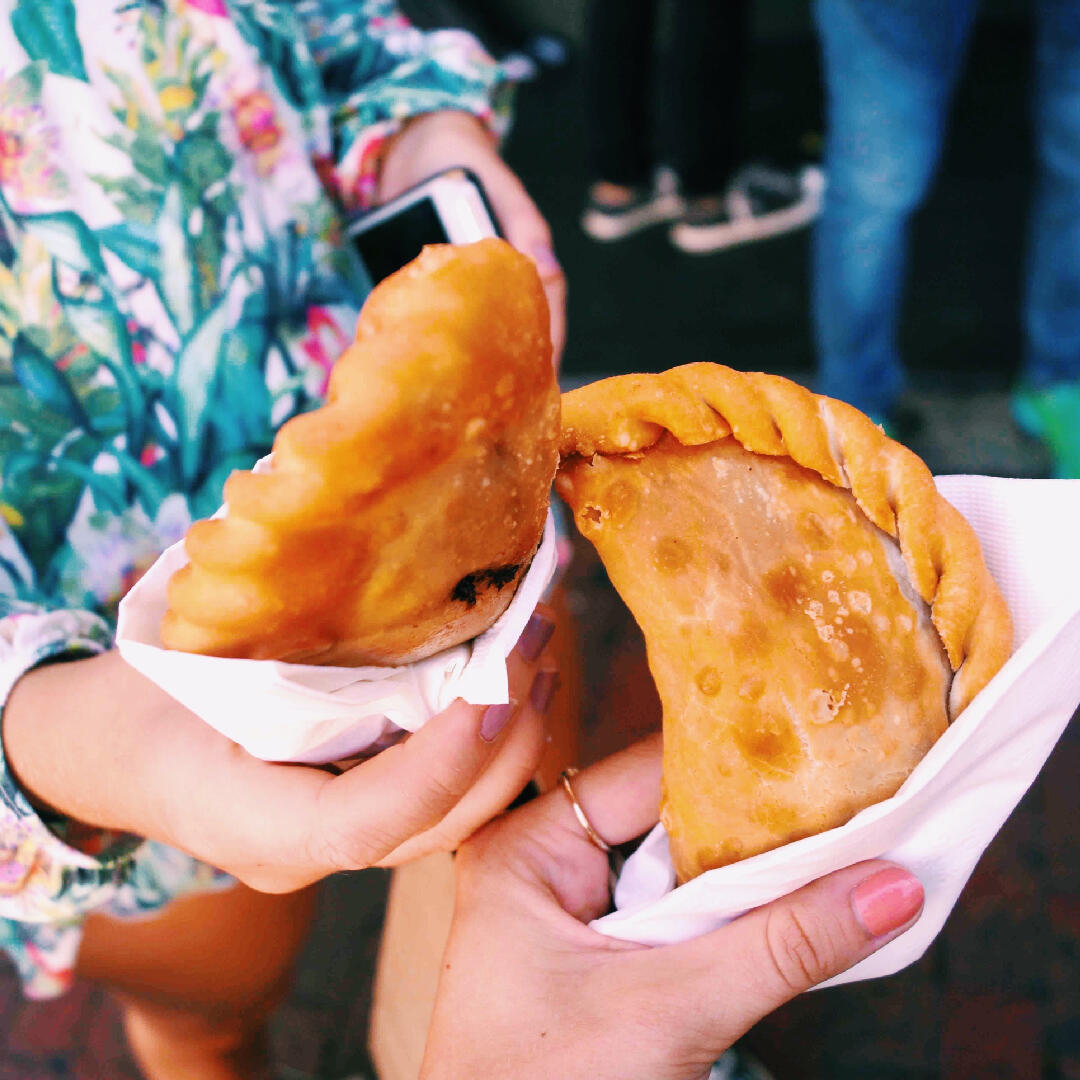 A woman participating in a Miami Food Tour, holding a half-eaten empanada.