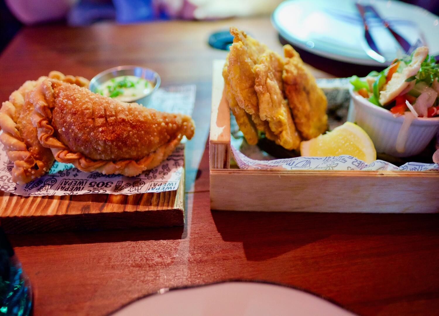 Two trays of food on a wooden table during a Miami Food Tour.