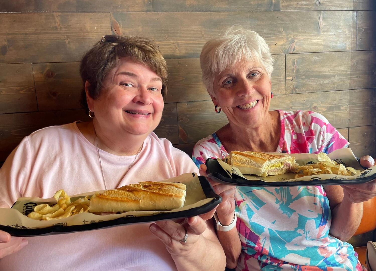 Two women enjoying Miami Food Tours with plates of food.