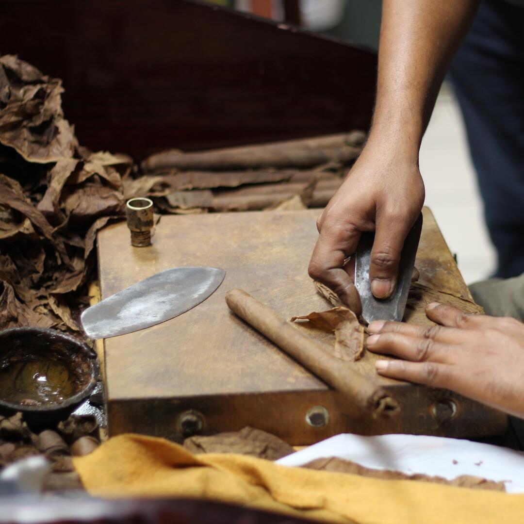 A man is slicing a piece of tobacco during a Cullenary Tour.