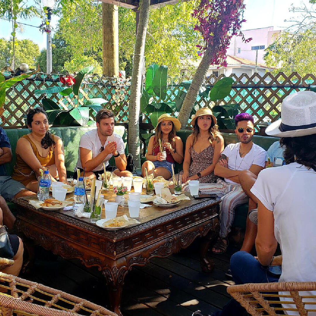 A group of people sitting around a table, enjoying a Miami Food Tour.