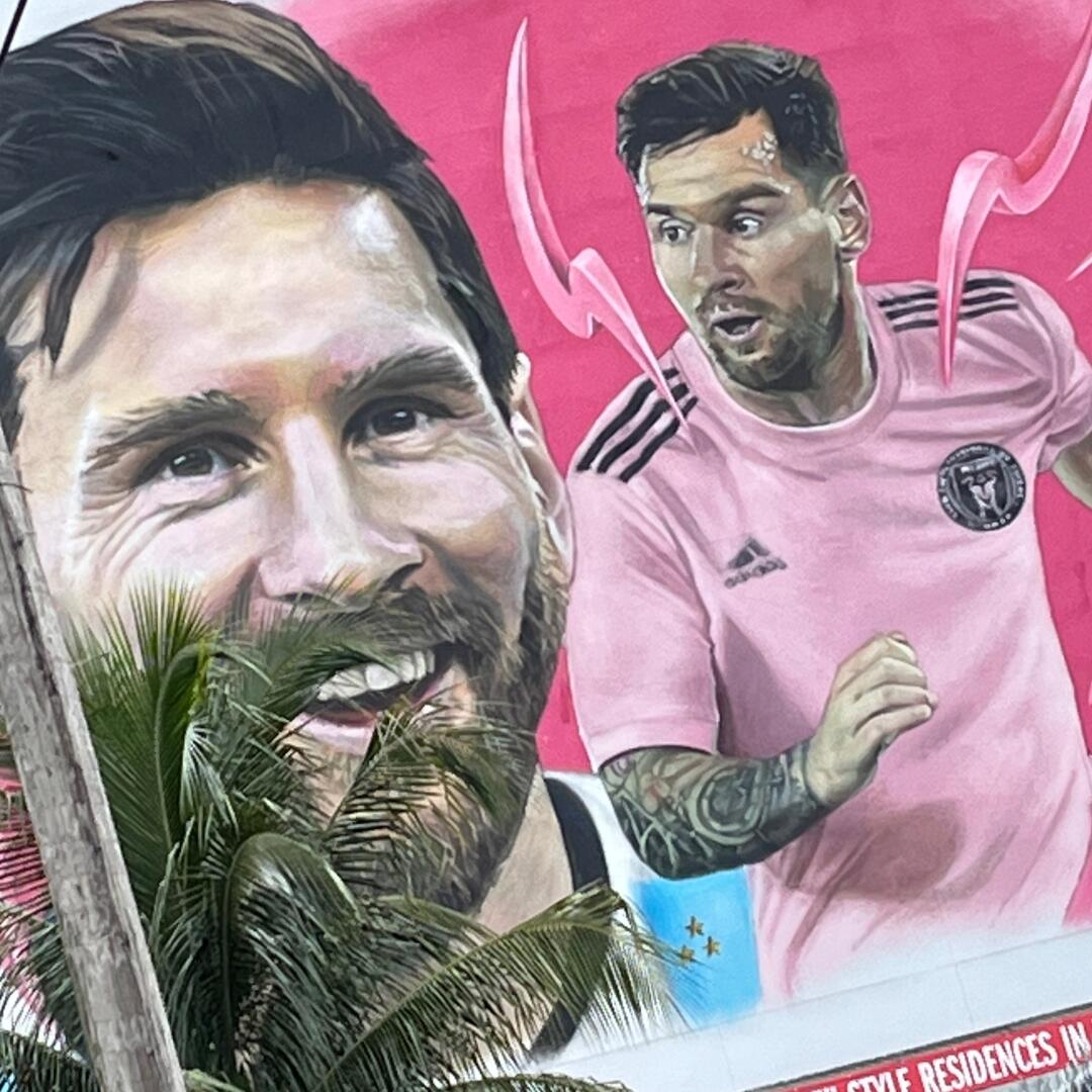 A mural of a soccer player is painted on a wall, perfect for group tours.