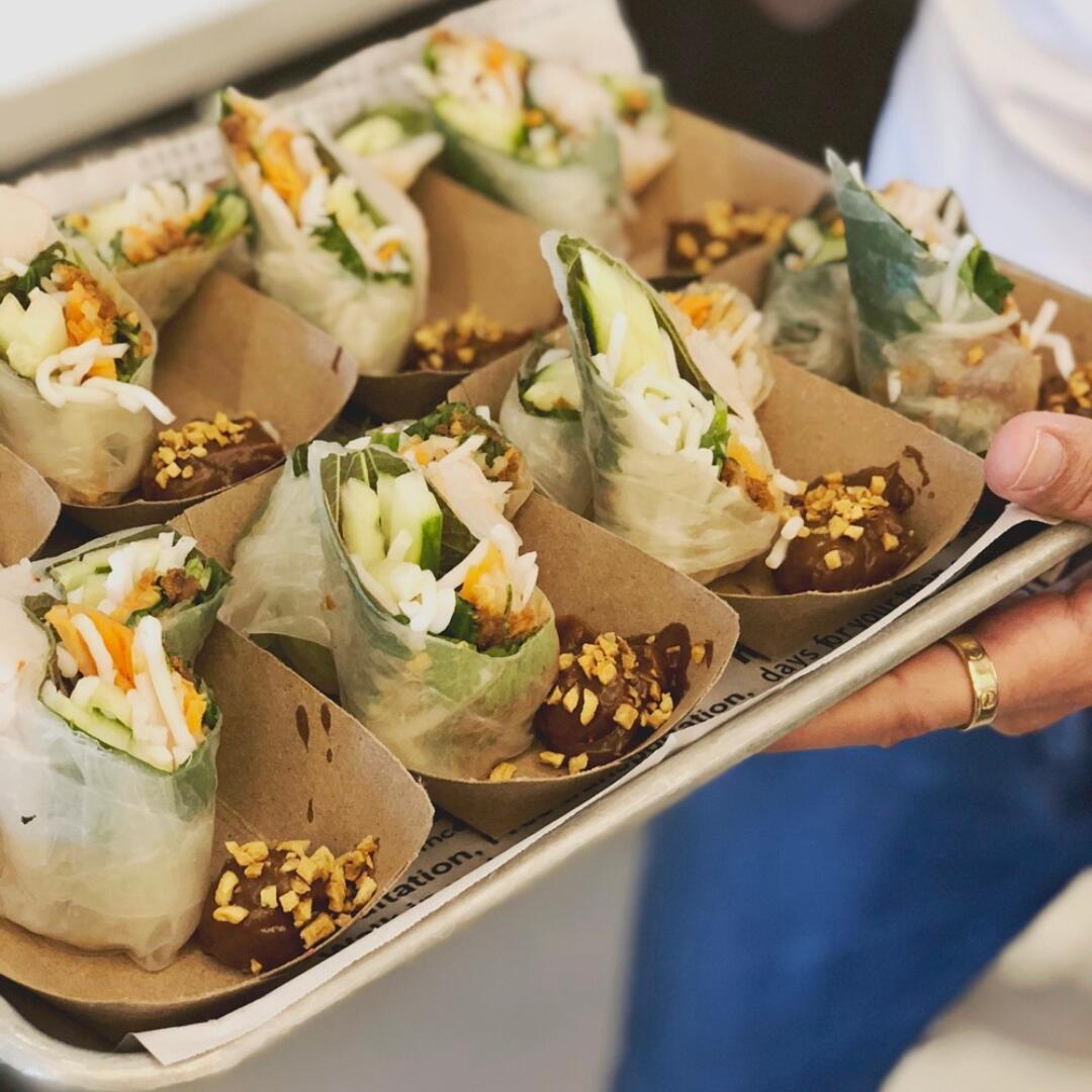 A person is holding a tray of spring rolls during a private culinary tour.