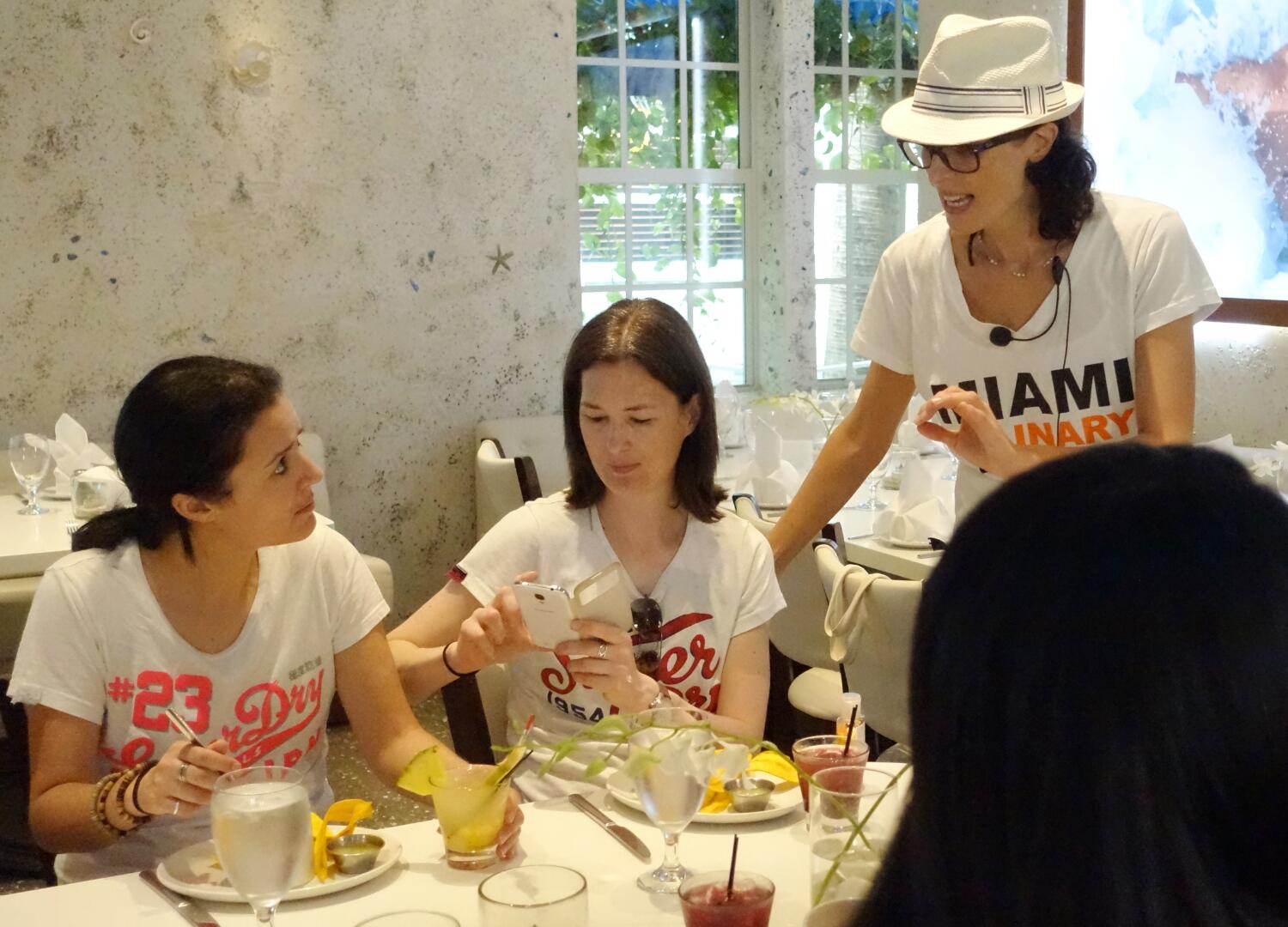 A group of women are sitting at a table enjoying a delicious culinary feast during a private Miami food tour.
