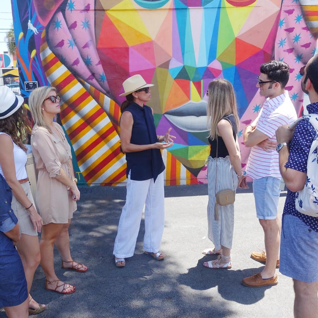  Description: A group of people on a Group Tour standing in front of a colorful mural.