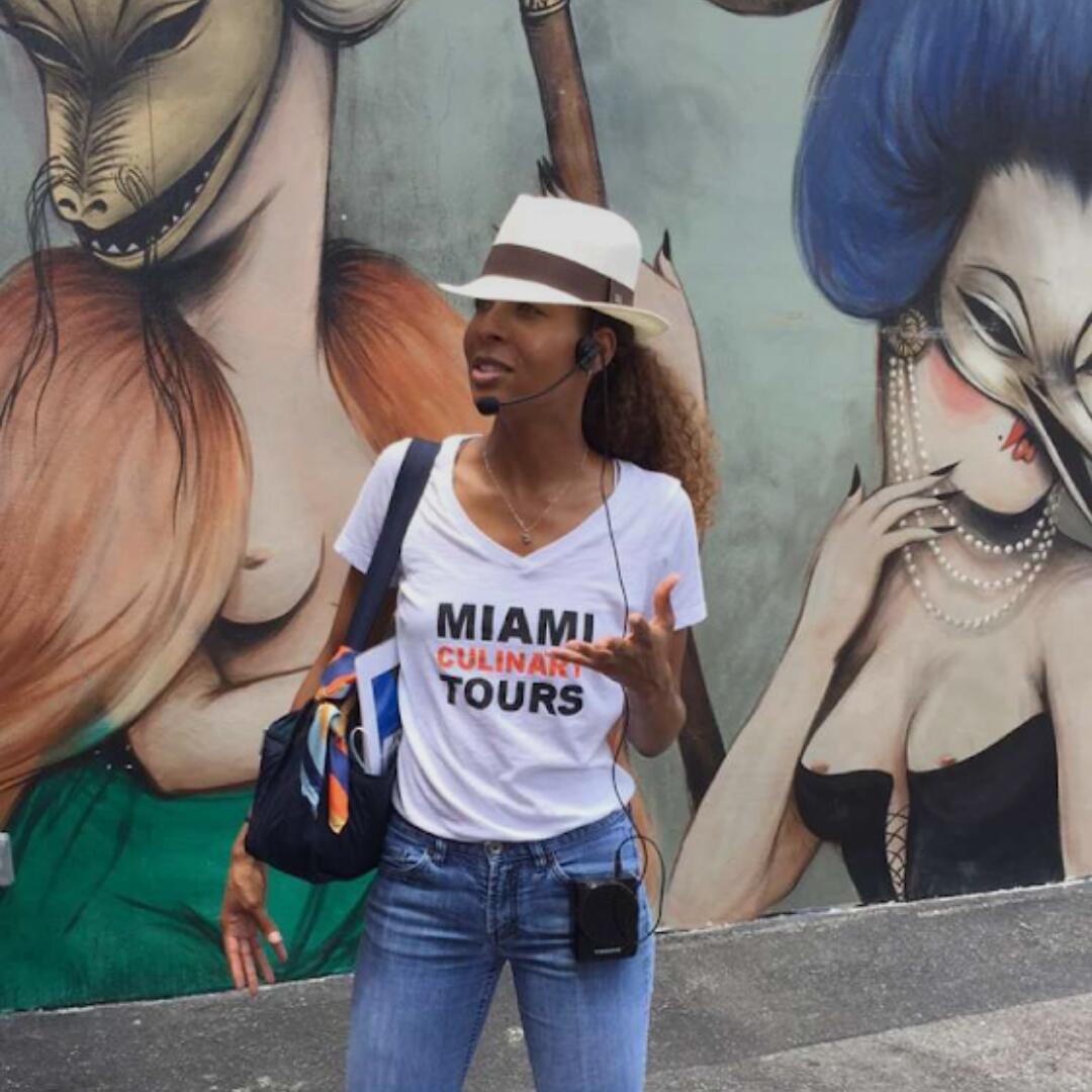 A woman standing in front of a mural that says Miami Private Tours.