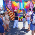 A group of people standing in front of a colorful mural during a private tour.