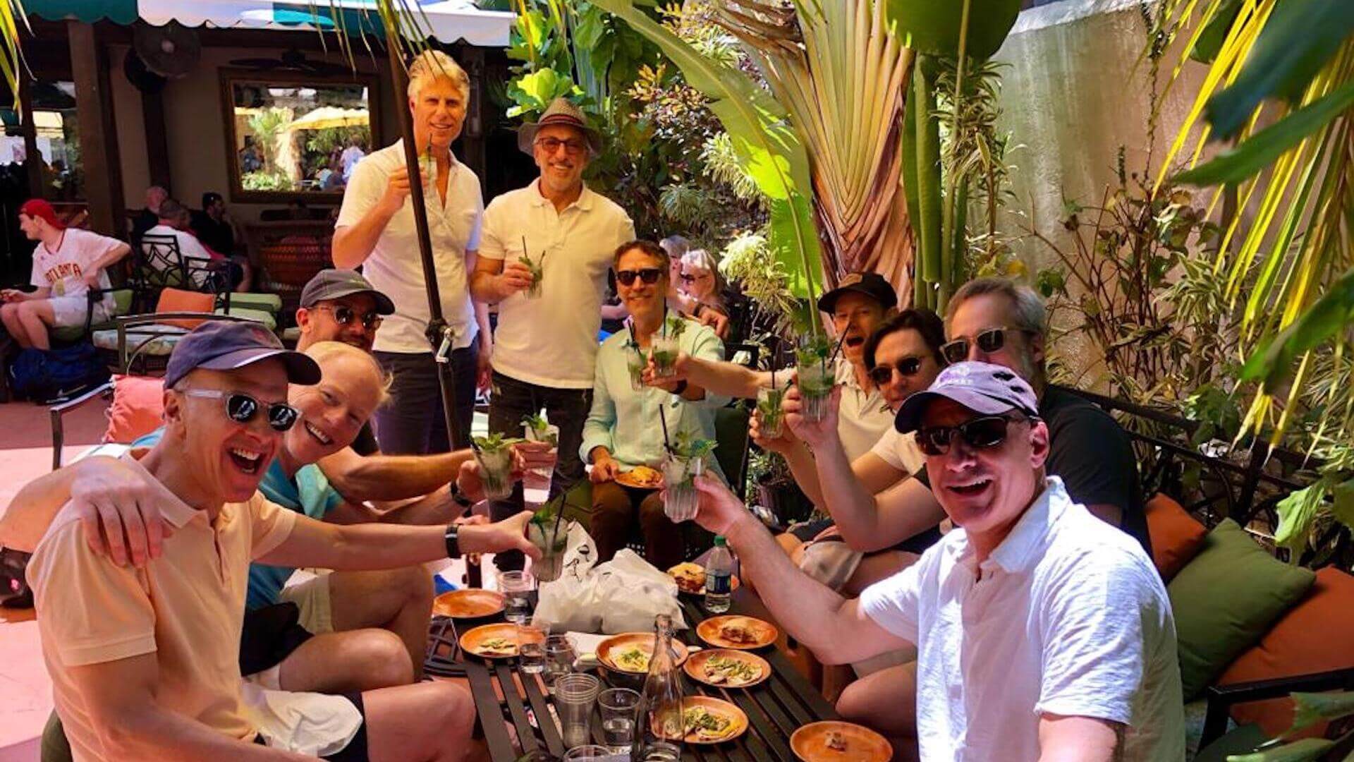 A group of people enjoying drinks and food at an outdoor restaurant setting.