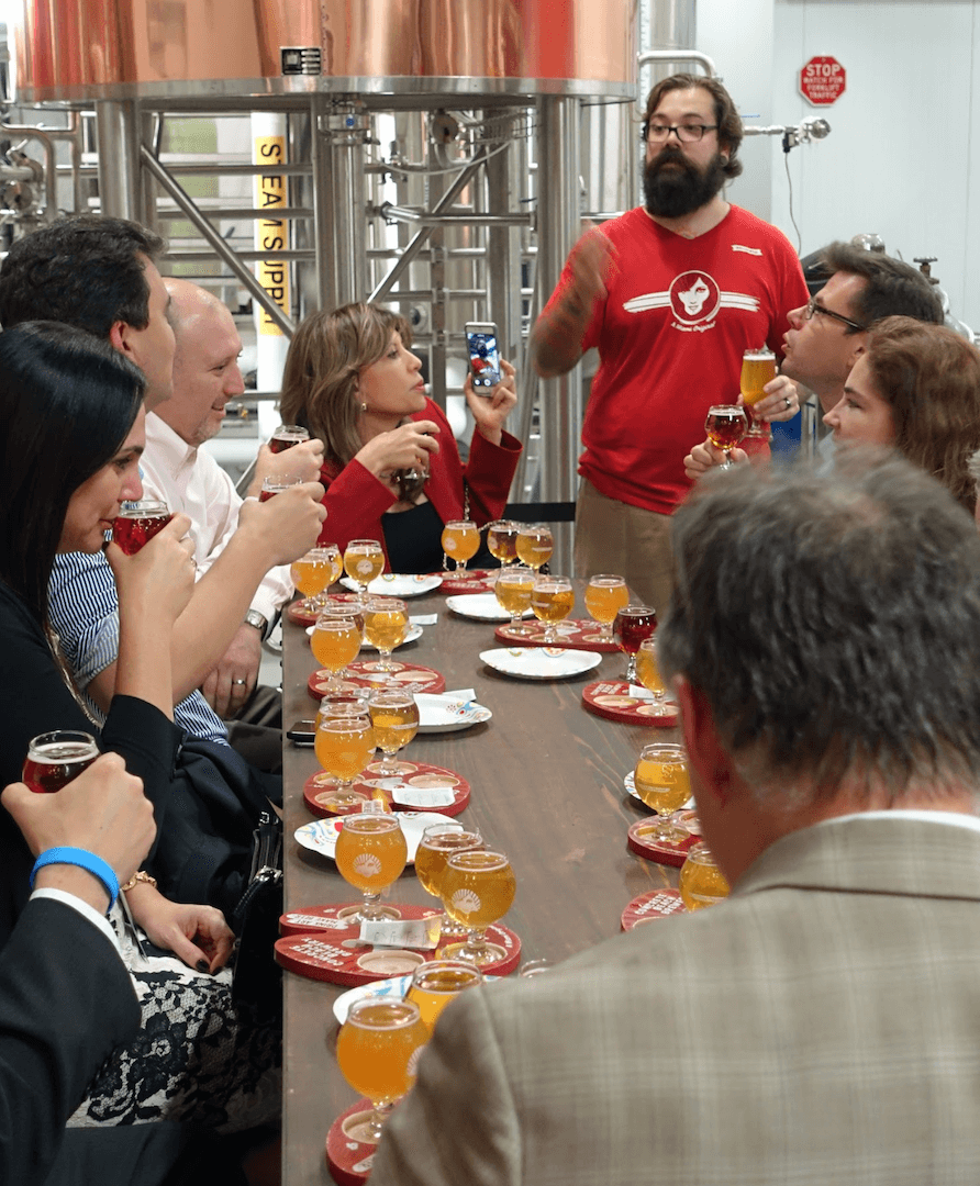 A brewery tour guide explaining the brewing process to a group of interested guests tasting different beers.